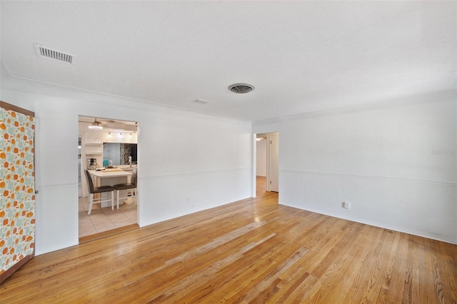 unfurnished room featuring visible vents, baseboards, and hardwood / wood-style floors
