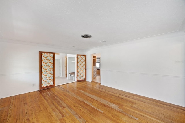 spare room with baseboards, visible vents, and light wood-type flooring