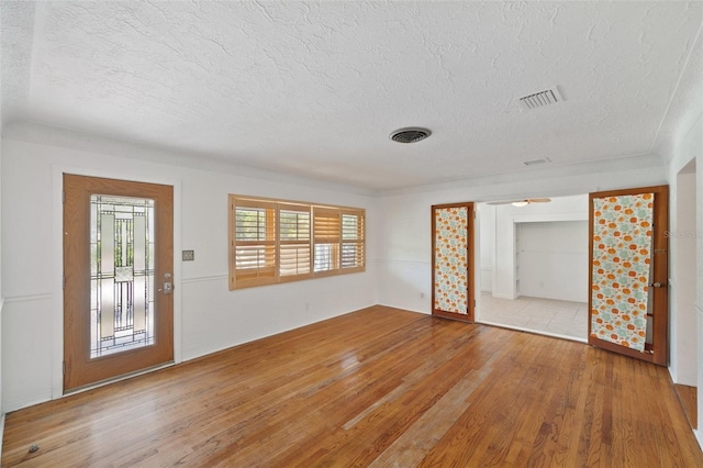 spare room featuring visible vents, a textured ceiling, and wood finished floors