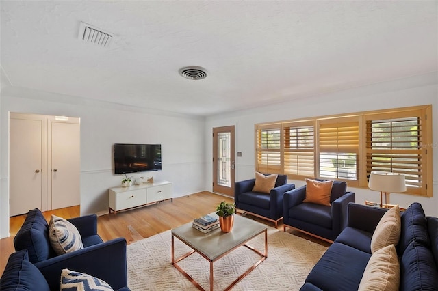 living area with a wealth of natural light, light wood-style flooring, and visible vents
