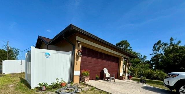 150 Tompkins St, Port Charlotte, FL 33954 - view of property exterior featuring driveway, fence, and a garage