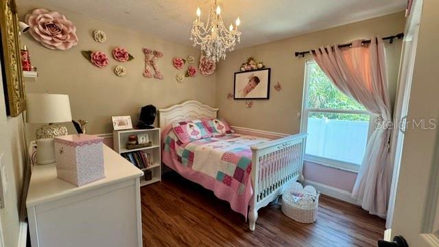 150 Tompkins St, Port Charlotte, FL 33954 - bedroom with dark wood-style floors, an inviting chandelier, and baseboards