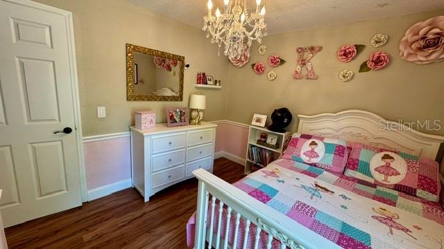 150 Tompkins St, Port Charlotte, FL 33954 - bedroom with baseboards, a notable chandelier, and dark wood-type flooring