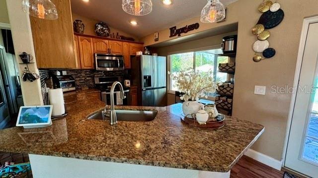 150 Tompkins St, Port Charlotte, FL 33954 - kitchen featuring a sink, dark stone countertops, brown cabinetry, tasteful backsplash, and appliances with stainless steel finishes