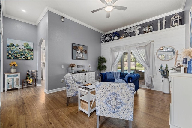 living area featuring arched walkways, a ceiling fan, ornamental molding, and wood finished floors