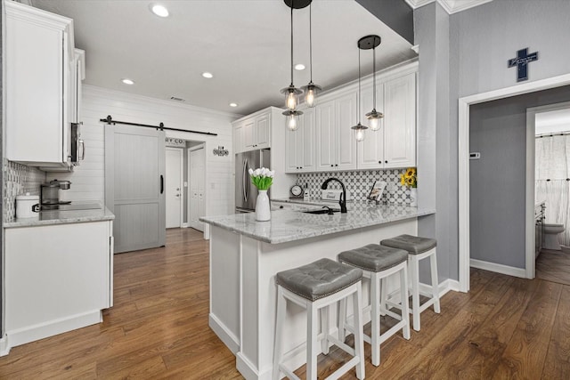 kitchen with a barn door, a sink, appliances with stainless steel finishes, and decorative backsplash