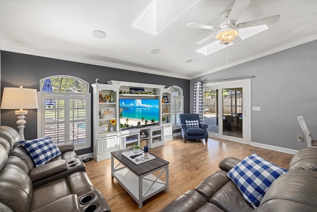 living area with a healthy amount of sunlight, crown molding, and lofted ceiling with skylight