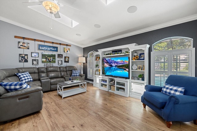 living room featuring a ceiling fan, ornamental molding, wood finished floors, and vaulted ceiling with skylight