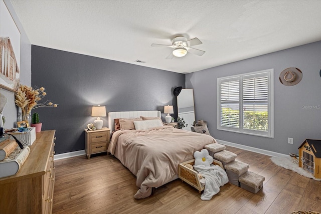 bedroom featuring ceiling fan, baseboards, visible vents, and wood finished floors