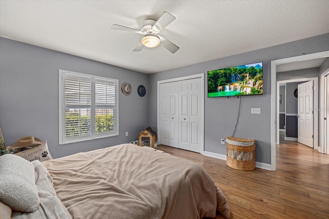 bedroom with baseboards, ceiling fan, a closet, and wood finished floors