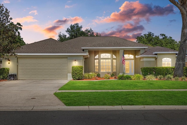 ranch-style house with concrete driveway, a lawn, stucco siding, and a garage