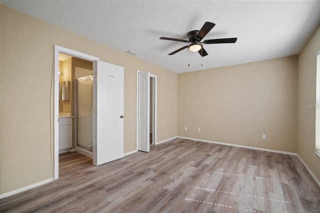 unfurnished bedroom with baseboards, visible vents, wood finished floors, and ensuite bathroom