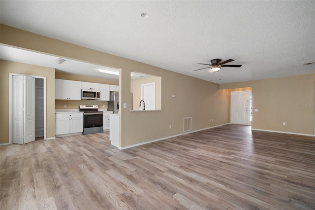 unfurnished living room with visible vents, ceiling fan, light wood-style floors, and a textured ceiling