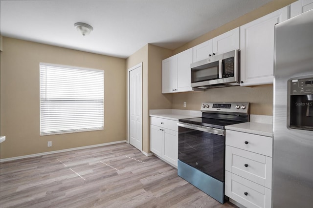 kitchen featuring white cabinets, appliances with stainless steel finishes, light countertops, baseboards, and light wood-type flooring