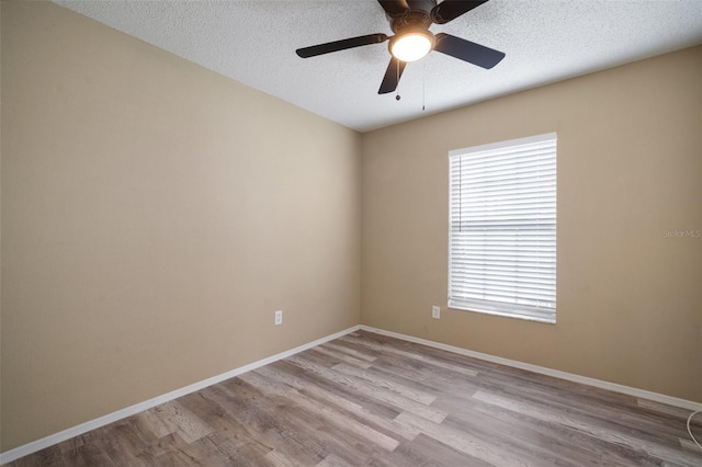 empty room with baseboards, wood finished floors, a wealth of natural light, and a textured ceiling