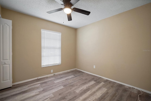 empty room featuring a ceiling fan, baseboards, wood finished floors, and a textured ceiling