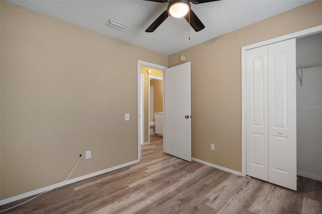 unfurnished bedroom with a closet, ceiling fan, visible vents, baseboards, and wood finished floors