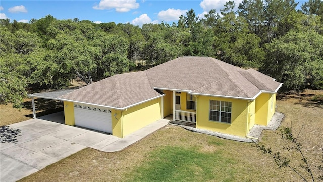 ranch-style house with roof with shingles, a garage, stucco siding, a front yard, and driveway