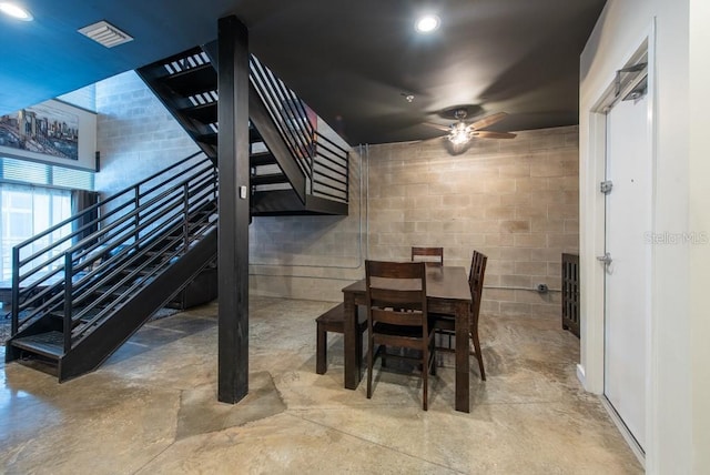 5008 S Macdill Ave Unit 10, Tampa, FL 33611 - dining area with stairway, a ceiling fan, concrete block wall, and unfinished concrete flooring