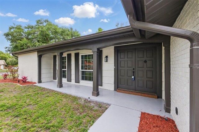 12601 Stone House Loop, Hudson, FL 34667 - entrance to property featuring a yard, a porch, and brick siding