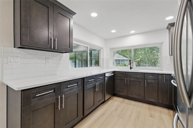 12601 Stone House Loop, Hudson, FL 34667 - kitchen featuring decorative backsplash, dark brown cabinetry, light wood-type flooring, a sink, and stainless steel appliances