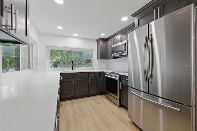 12601 Stone House Loop, Hudson, FL 34667 - kitchen featuring a sink, light countertops, stainless steel appliances, decorative backsplash, and light wood-type flooring