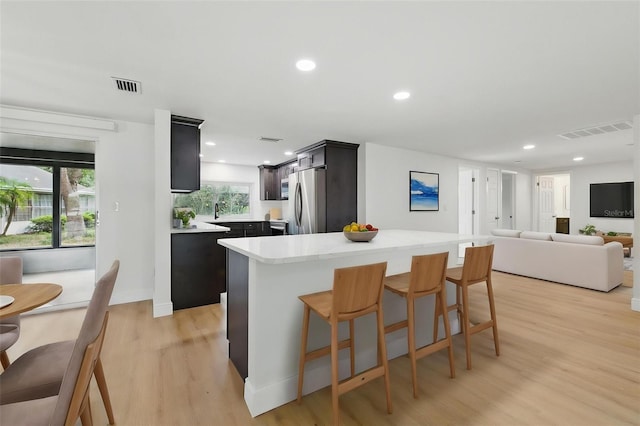 12601 Stone House Loop, Hudson, FL 34667 - kitchen featuring visible vents, freestanding refrigerator, a kitchen bar, and light countertops