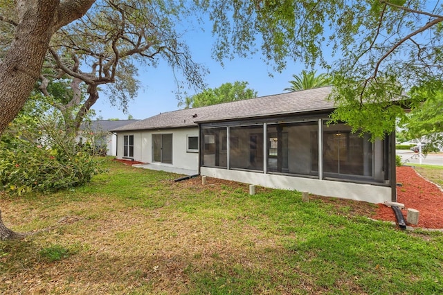 12601 Stone House Loop, Hudson, FL 34667 - back of property featuring a sunroom, roof with shingles, stucco siding, and a yard