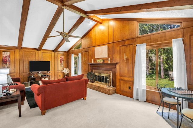 living room with wooden walls, light carpet, a brick fireplace, a ceiling fan, and vaulted ceiling with beams