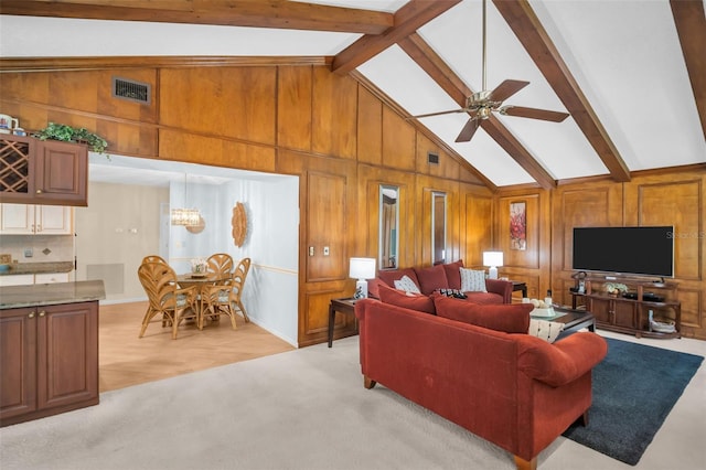living room with wooden walls, visible vents, beam ceiling, and ceiling fan with notable chandelier