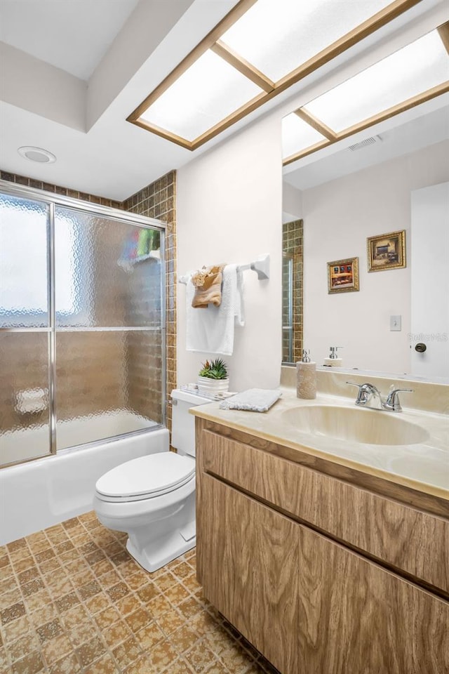 bathroom with toilet, visible vents, bath / shower combo with glass door, and vanity