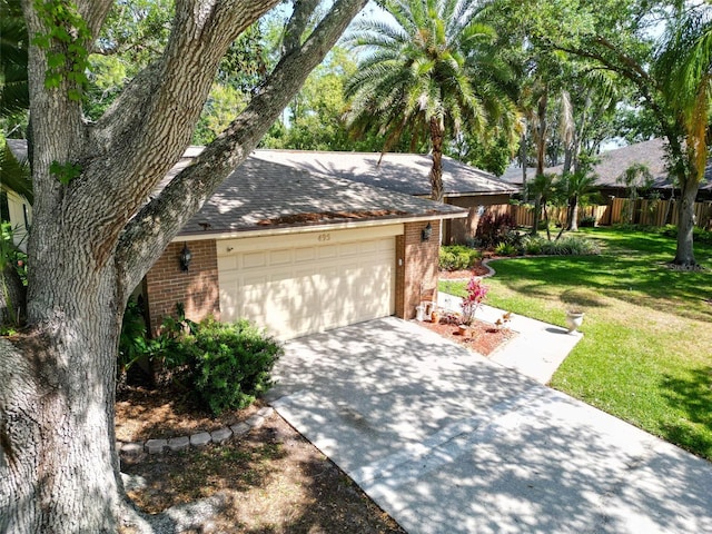 view of front of home with a front lawn, fence, brick siding, an attached garage, and driveway
