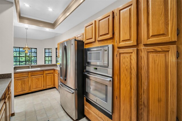 10 Greenhaven Cir, Oldsmar, FL 34677 - kitchen with appliances with stainless steel finishes, a raised ceiling, a sink, ornamental molding, and brown cabinetry