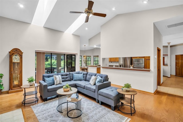 10 Greenhaven Cir, Oldsmar, FL 34677 - living area with high vaulted ceiling, ceiling fan, a skylight, light wood-style flooring, and baseboards