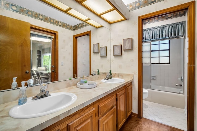 10 Greenhaven Cir, Oldsmar, FL 34677 - bathroom featuring toilet, wallpapered walls, double vanity,  shower combination, and wood finished floors