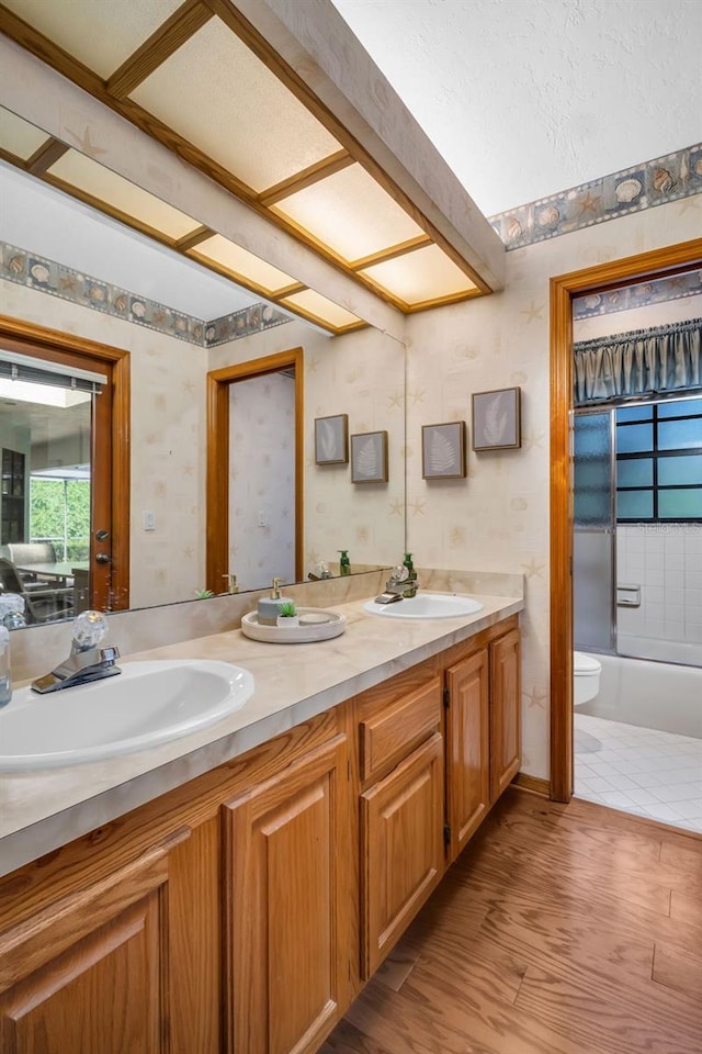 10 Greenhaven Cir, Oldsmar, FL 34677 - full bath with toilet, double vanity, wallpapered walls, bathtub / shower combination, and wood finished floors