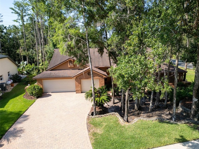 10 Greenhaven Cir, Oldsmar, FL 34677 - view of property hidden behind natural elements with an attached garage, decorative driveway, brick siding, a front lawn, and cooling unit