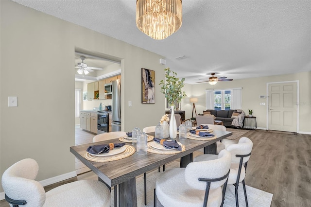 dining room with a ceiling fan, a textured ceiling, baseboards, and a chandelier
