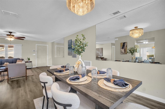 dining room with a chandelier, ceiling fan, a textured ceiling, baseboards, and wood finished floors