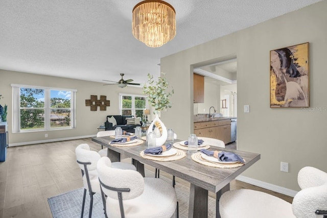 dining area featuring ceiling fan, a textured ceiling, baseboards, and a chandelier