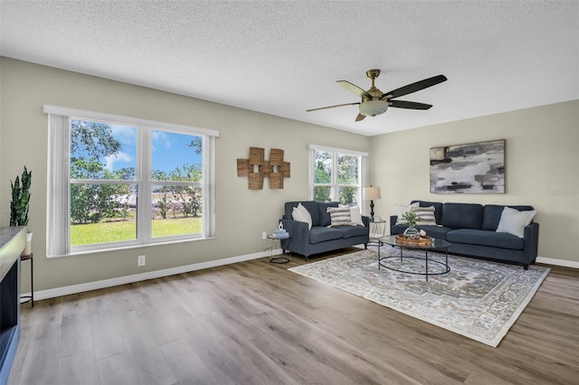 living room with wood finished floors, a textured ceiling, ceiling fan, and baseboards