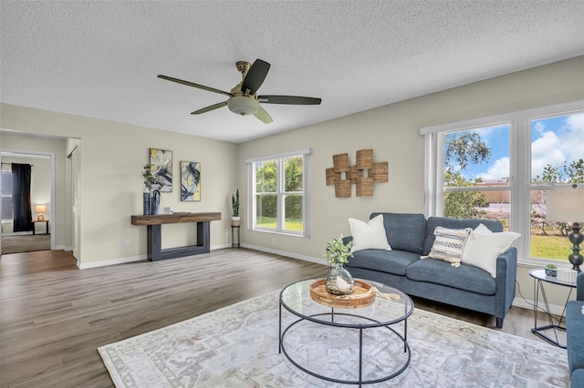 living area with wood finished floors, baseboards, a ceiling fan, and a textured ceiling