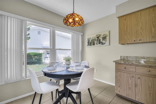 dining space featuring baseboards, light tile patterned floors, and a textured ceiling