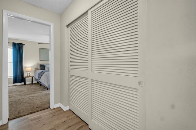 corridor featuring baseboards and light wood finished floors