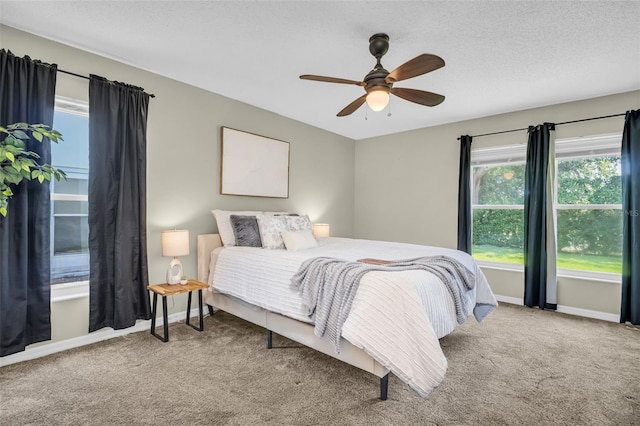 bedroom with carpet floors, ceiling fan, baseboards, and a textured ceiling