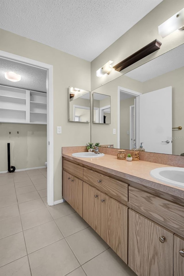 full bathroom featuring tile patterned flooring, a textured ceiling, double vanity, toilet, and baseboards
