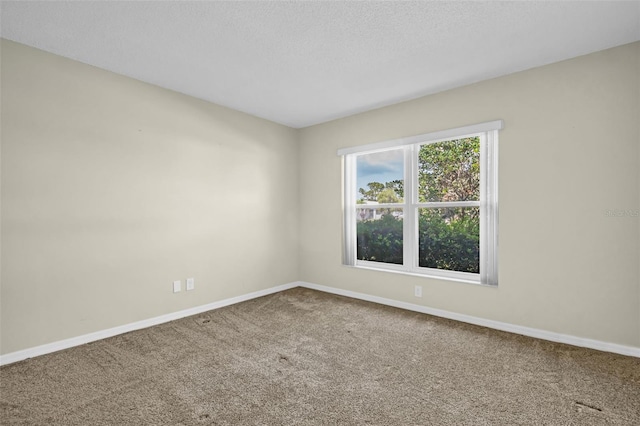 unfurnished room with carpet, baseboards, and a textured ceiling