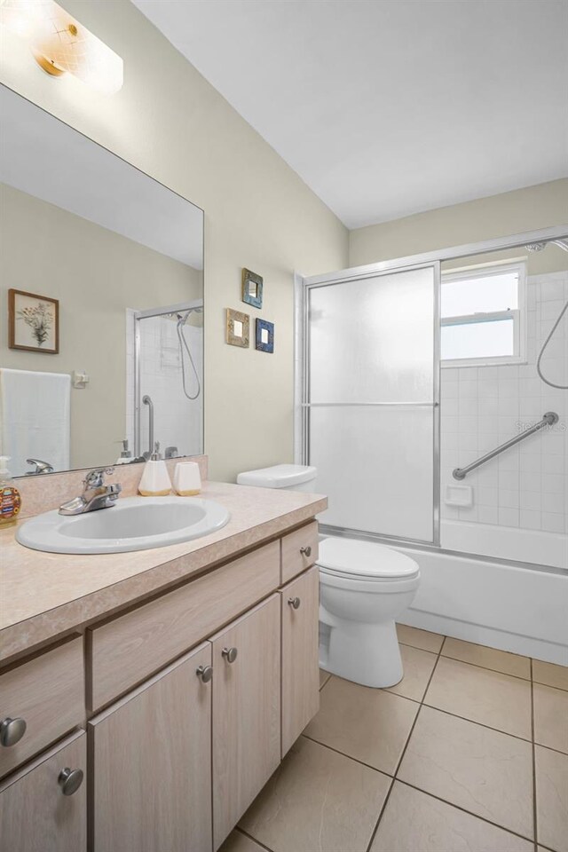 full bath with tile patterned flooring, vanity, toilet, and combined bath / shower with glass door
