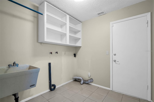 laundry room featuring a textured ceiling, baseboards, light tile patterned floors, and hookup for a washing machine