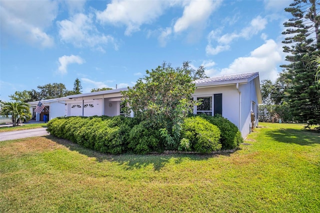 view of property exterior featuring stucco siding, a yard, and driveway